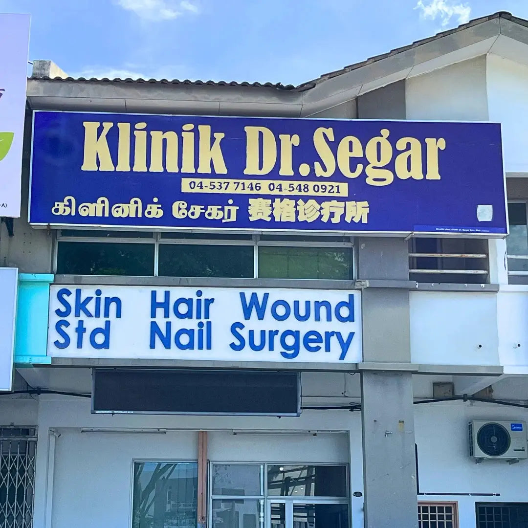 Klinik Dr. SEGAR signboard with contact numbers and services offered on a building.