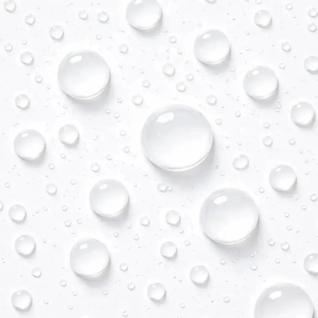Close-up of clear water droplets on a white surface, symbolizing skin hydration